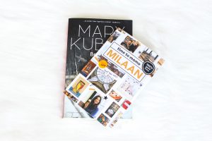 A travel guide to Milan laying on top of a book from Mary Kubica