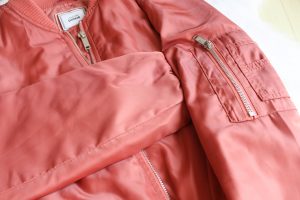 A close up from a orange coper bomber jacket